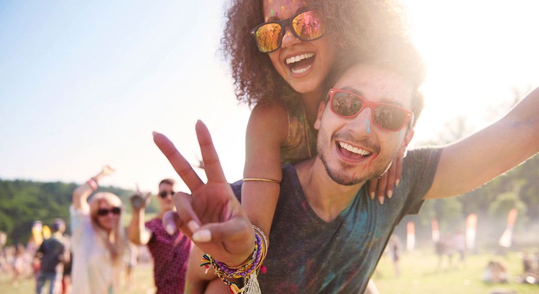 Festival Vaping Guide Blog Cover. Image Showing Woman on mans shoulders enjoying a festival in the sun.