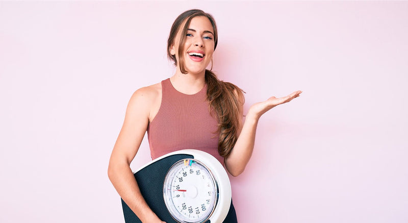 Woman holding weighing scales in one hand with their other hand held out with a questionable look on her face.